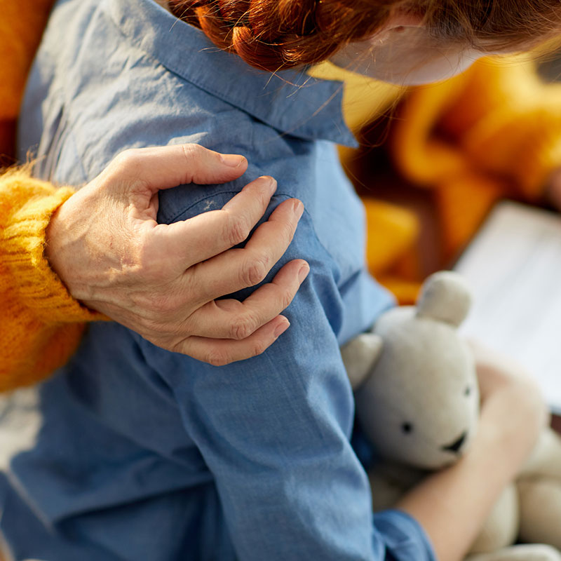 Family Therapy at Mirjam Quinn & Associates, therapist embracing a child holding a teddy bear