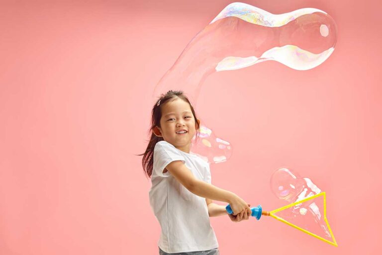 Practice the zones of regulation framework, young Asian girl smiling while playing with a giant bubble wand