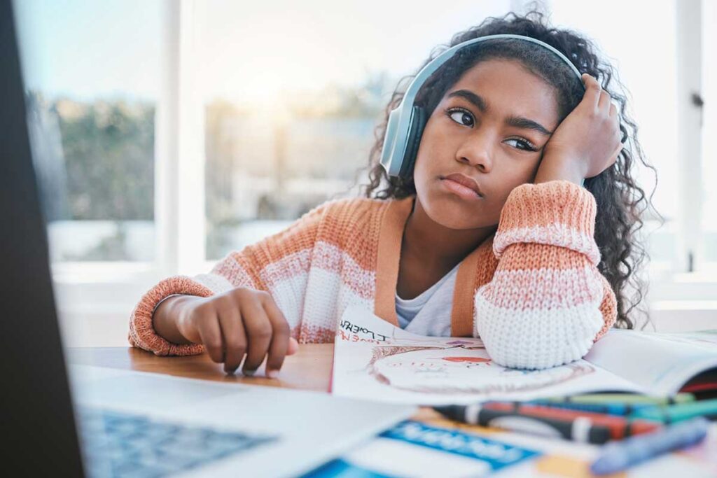 Support your child with AD/HD, elementary-aged girl looking bored while at a computer