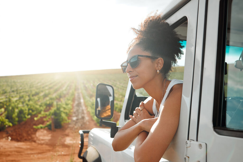 How late summer throws off your rhythm, woman sticking head outside of her vehicle window and enjoying the sunshine while parked