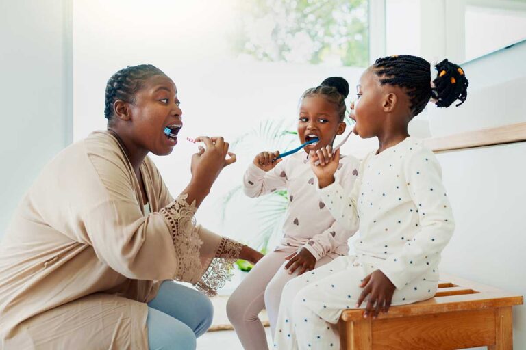 Soft Starts and Morning Routines, black parent with young children brushing their teeth together in the morning