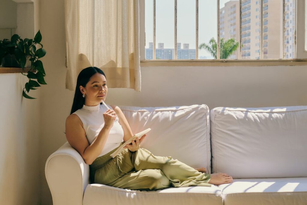Sit with Uncertainty, young woman on the couch with a notepad