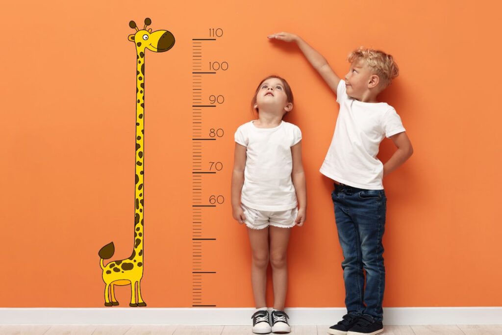 You’re Growing, Even If It Doesn’t Feel Like It, two children measuring each other on the wall